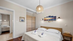 Un dormitorio con cama, lámpara colgante, una obra de arte en la pared y una mesita de noche.