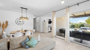 Una sala de estar moderna con sofá, mesa de comedor y cocina al fondo.