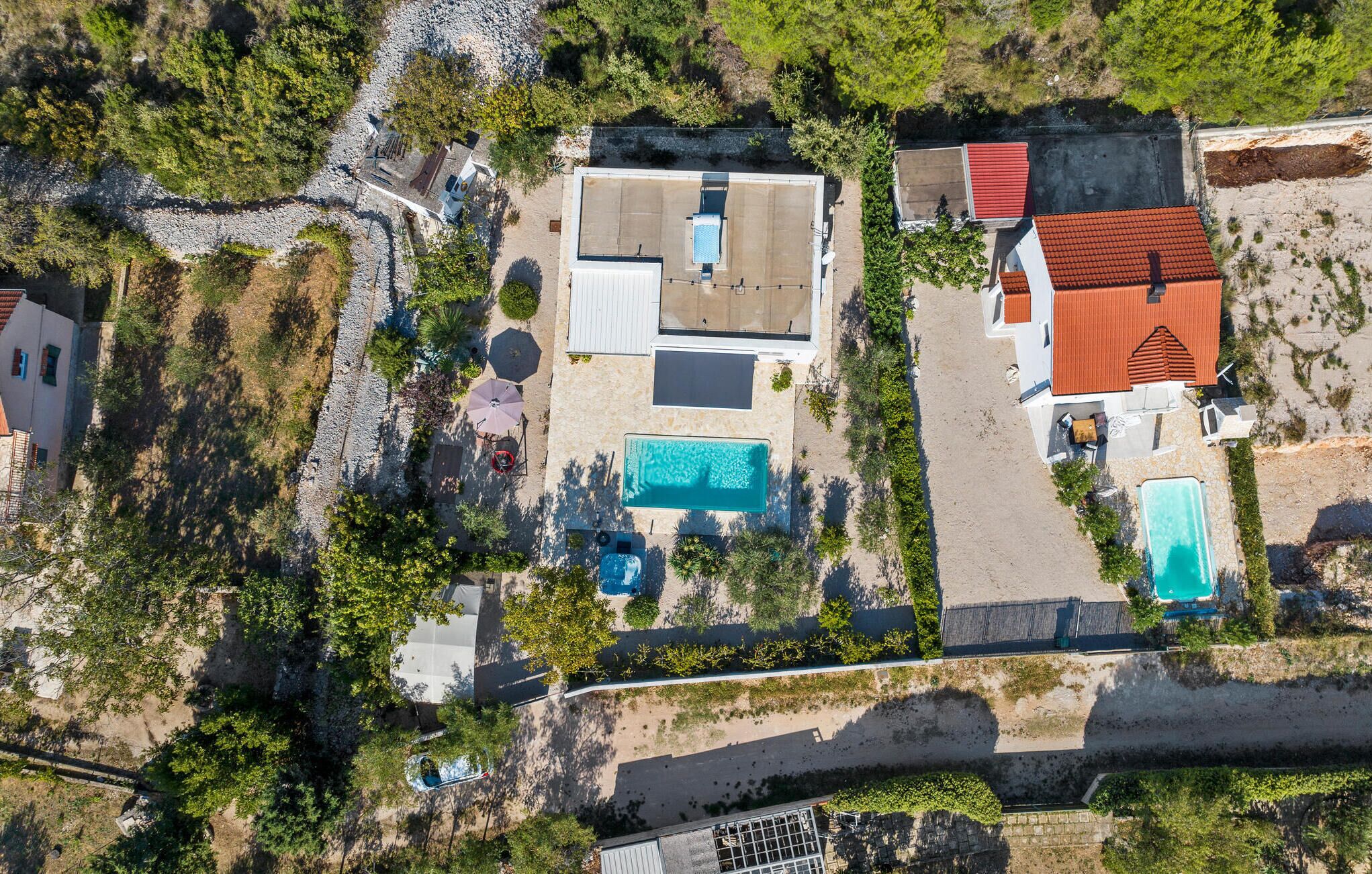 An aerial view of a residential area with multiple houses, a swimming pool, and a beach.
