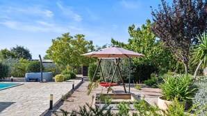 Un jardín con un columpio, una piscina y diversas plantas.