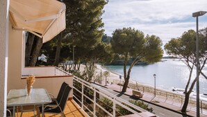 A balcony with a table and chairs, overlooking a beach and water. - Marina 6 - One Bedroom Apartment, Sleeps 4 (Roses)