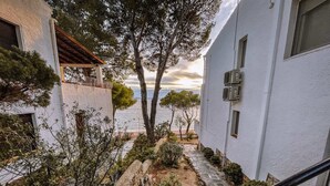 A coastal building with a stone pathway leading to a terrace overlooking the sea. - Marina 6 - One Bedroom Apartment, Sleeps 4 (Roses)