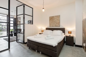 Un dormitorio moderno con una cama grande, lámparas de noche y un elemento decorativo en la pared.