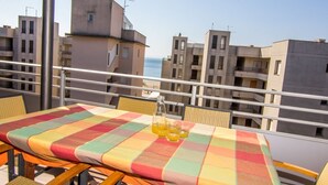 A balcony with a table set for two, overlooking a cityscape.