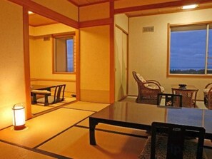 Una habitación japonesa tradicional con suelo de tatami, una mesa baja y vistas al exterior.