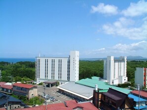 A large industrial building complex with multiple structures, surrounded by greenery and a clear sky.