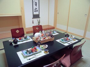 A conference room with a long table set for a meal, featuring traditional Japanese dishes and a decorative centerpiece.