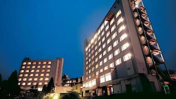 A multi-story hotel with illuminated windows and a balcony on the right side.