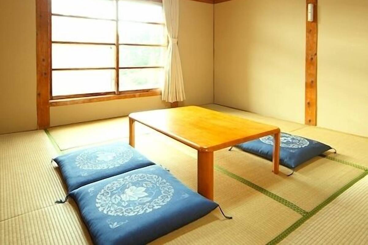 A traditional Japanese room with tatami flooring, a low wooden table, and cushions.
