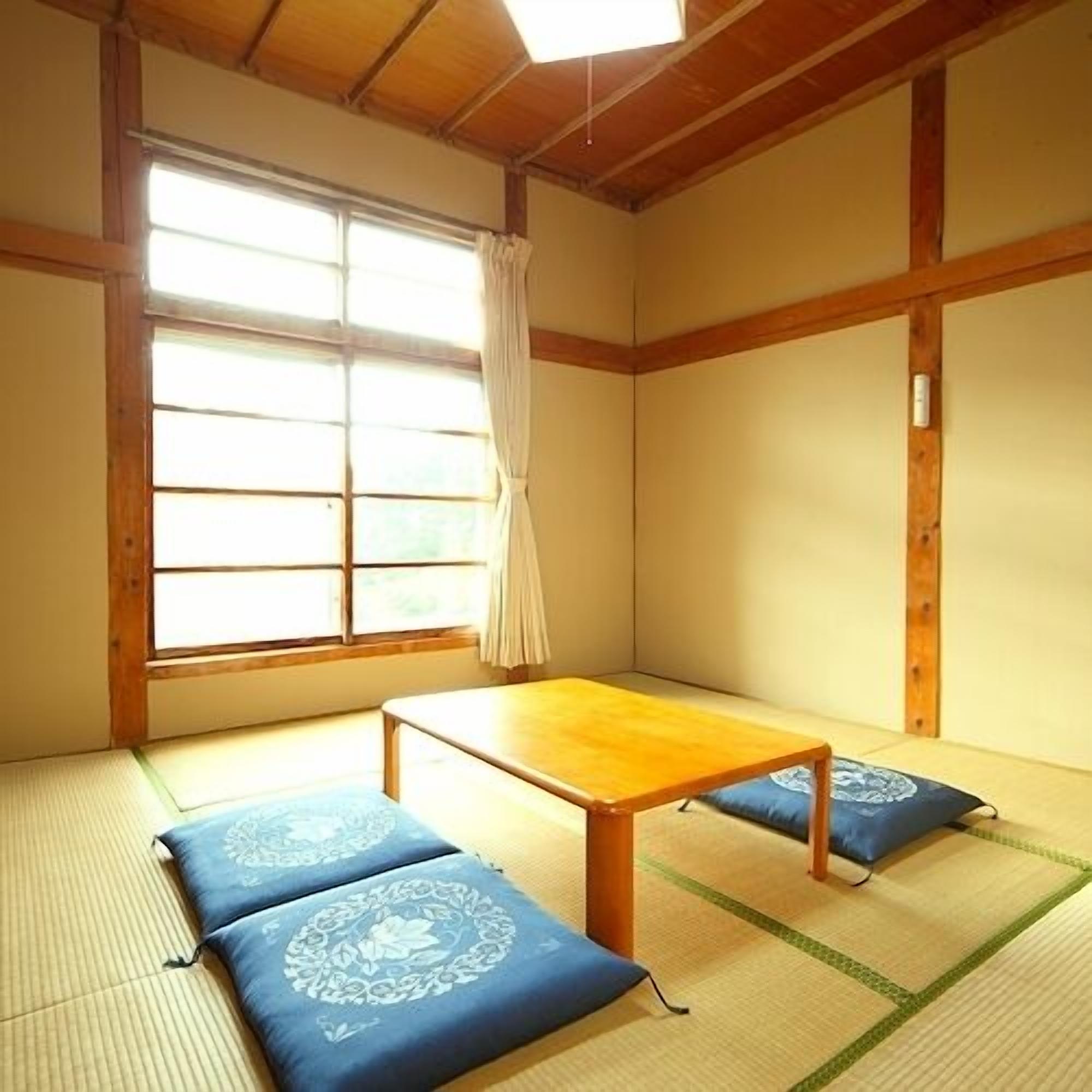 A traditional Japanese room with tatami flooring, a low wooden table, and cushions.