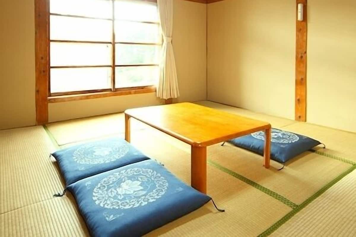 A traditional Japanese room with tatami flooring, a low wooden table, and cushions.