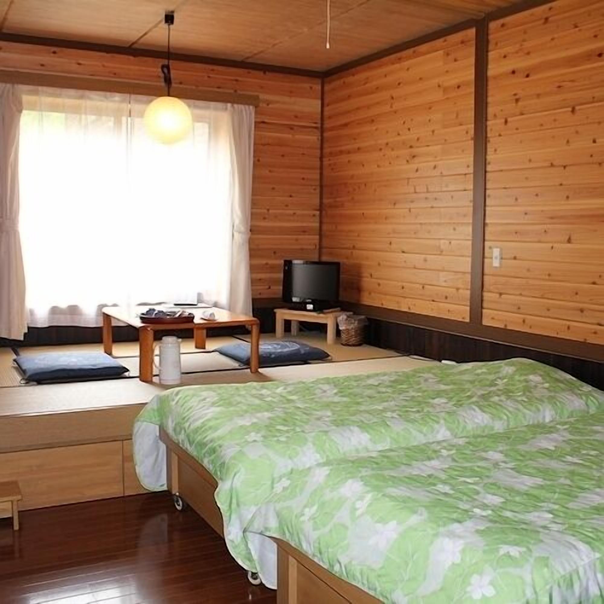 A room with a bed, a television, a small table, and a window with curtains.