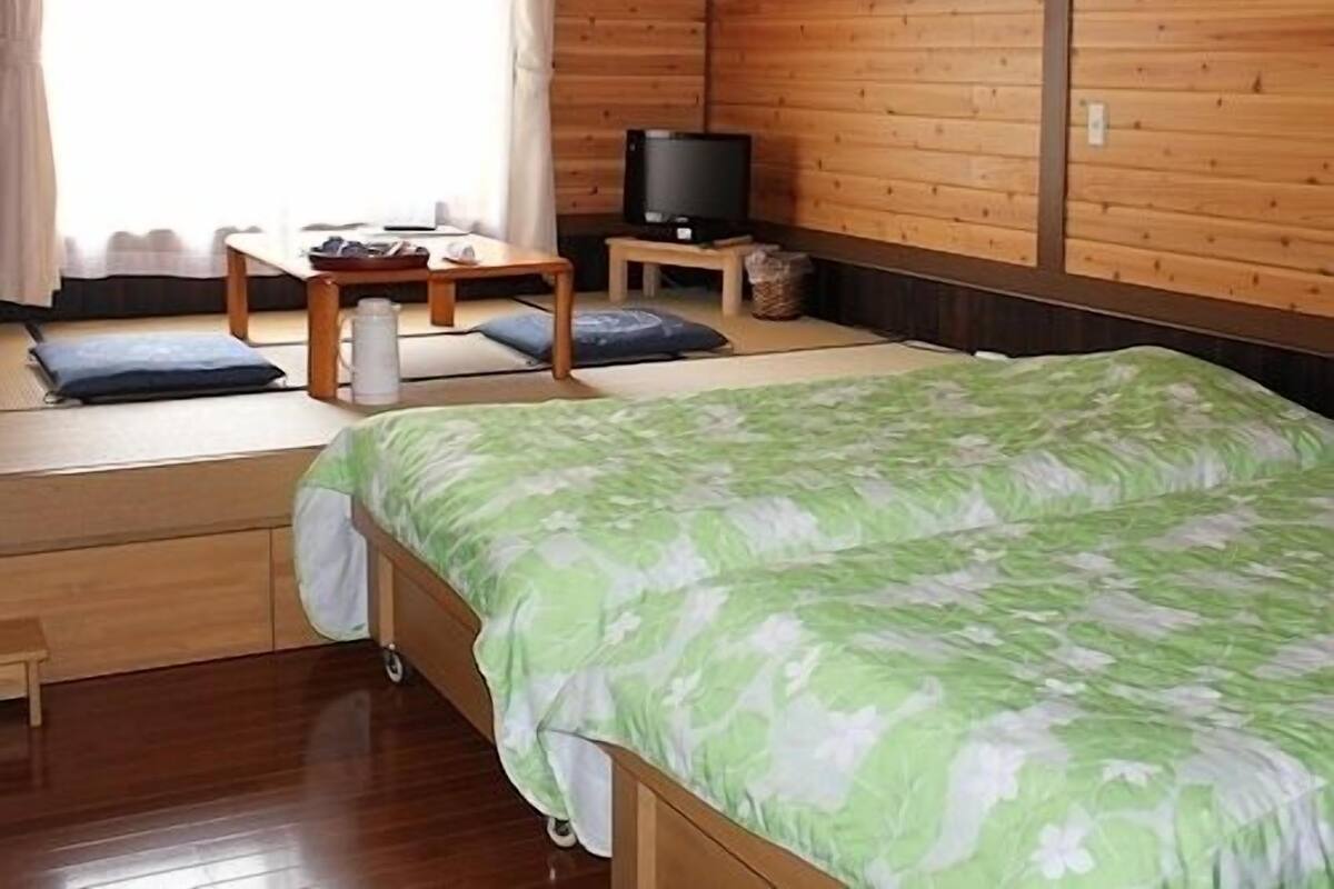 A room with a bed, a television, a small table, and a window with curtains.
