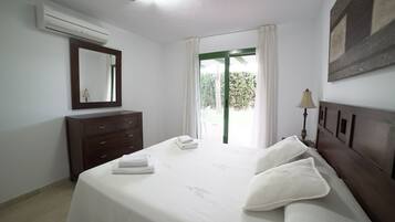 Habitación de hotel con cama, cómoda, espejo, ventana con cortinas y un cuadro en la pared.