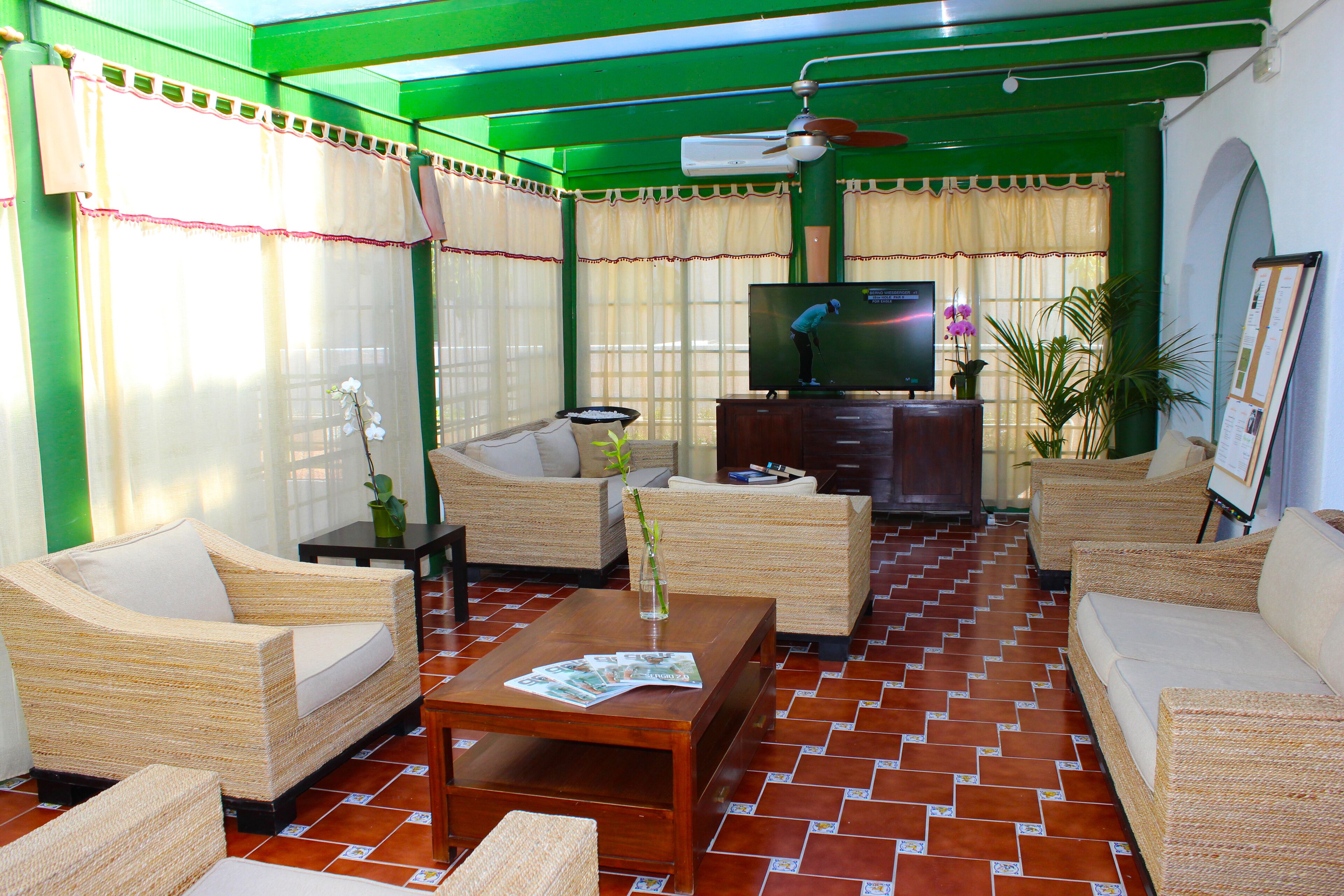 A living room with wicker furniture, a television, and a tiled floor.