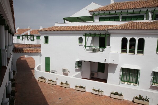 Un edificio blanco con contraventanas verdes y tejado de tejas.
