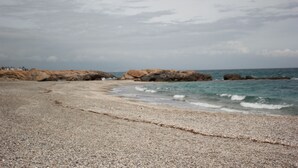 A pebble beach with rocky outcrops and calm sea. - Hotel Apartamentos Manilva Sun (Manilva)