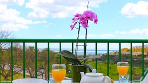 A table with breakfast items, a flower, and a view of the ocean. - Hotel Apartamentos Manilva Sun (Manilva)