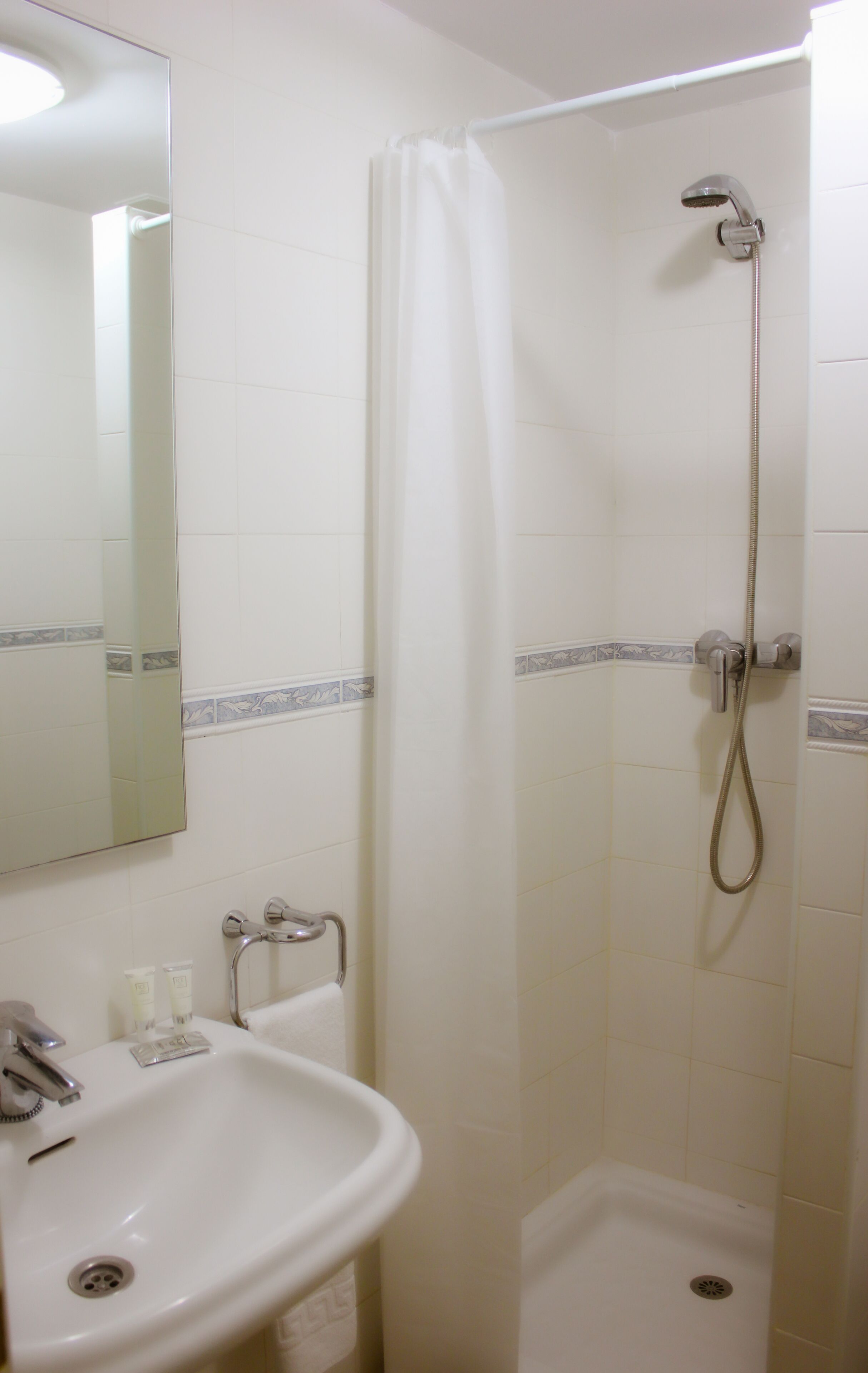 A bathroom with a shower, a sink, and a mirror.