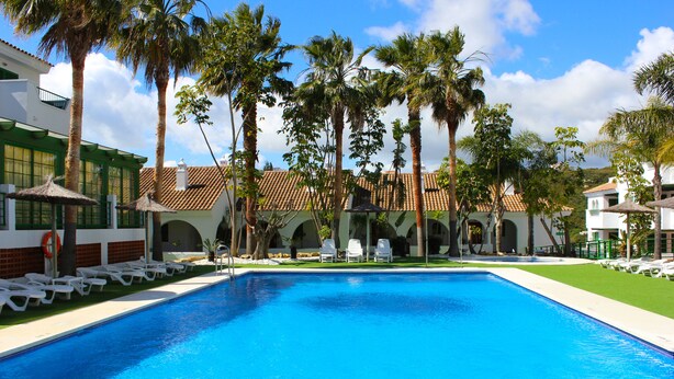 A swimming pool with white lounge chairs and palm trees. - Hotel Apartamentos Manilva Sun (Manilva)