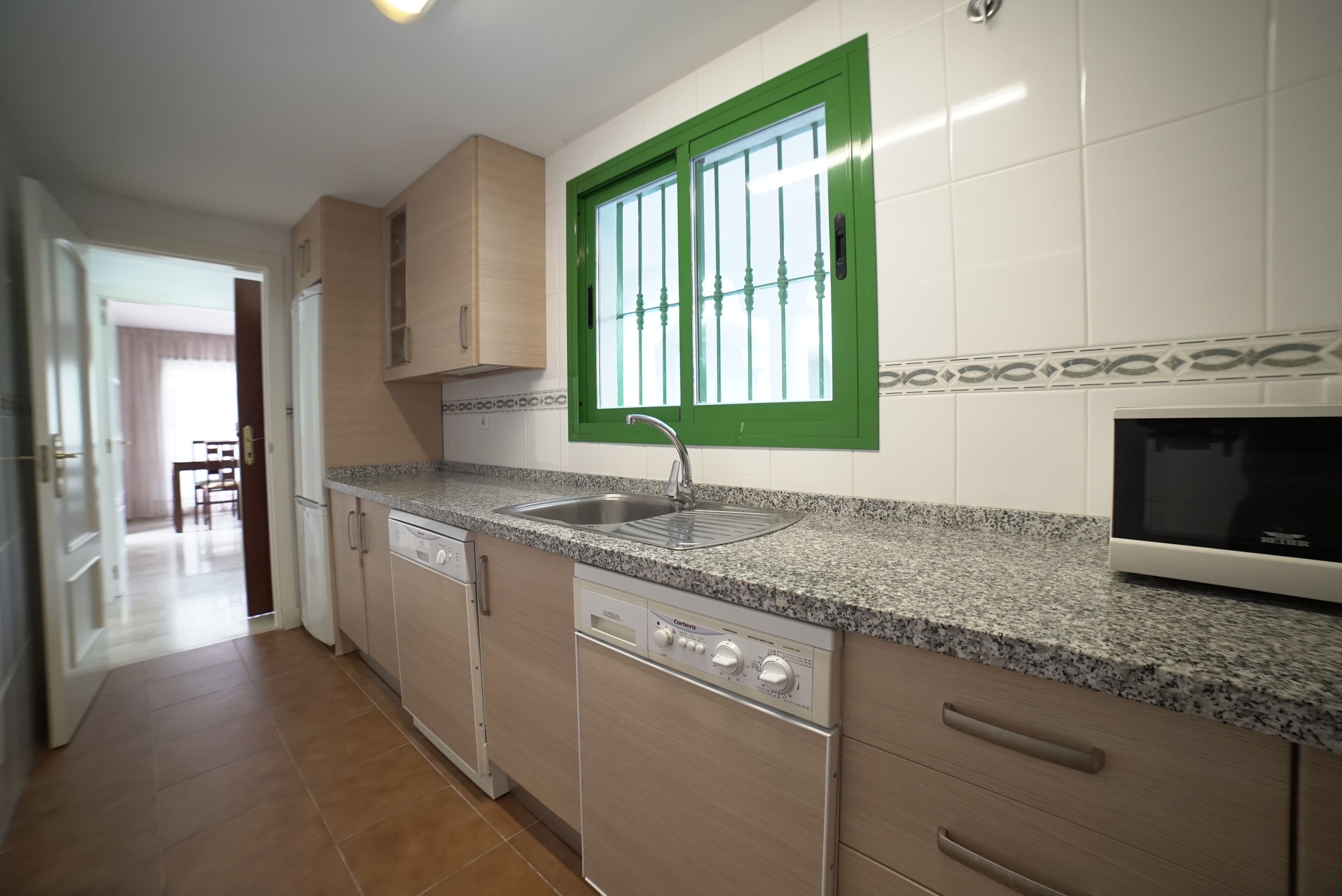 A kitchen with a dishwasher, a sink, and a microwave.
