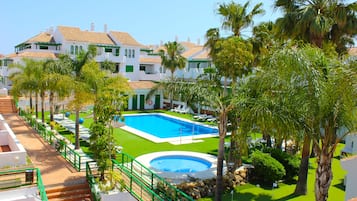 Una piscina al aire libre, sombrillas, sillones reclinables de piscina