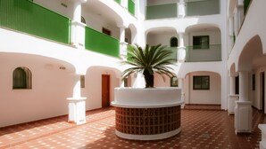 A spacious courtyard with a central fountain, surrounded by white walls and green balconies. - Hotel Apartamentos Manilva Sun (Manilva)