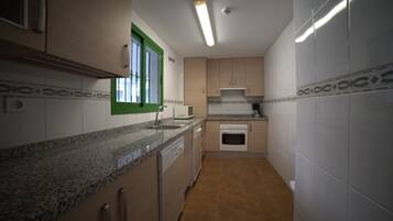 Una cocina compacta con encimera de granito, armarios blancos y una ventana con detalles verdes.