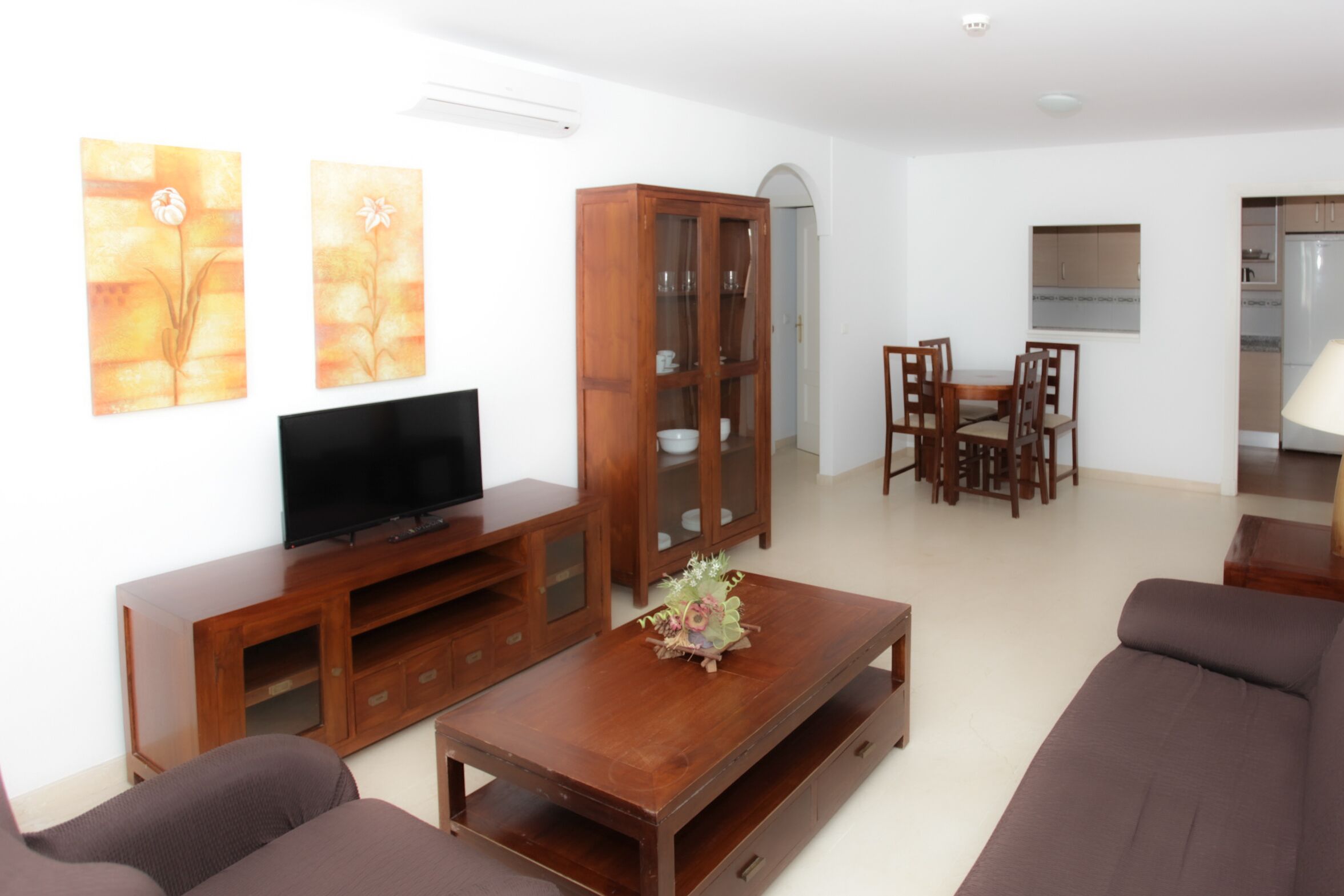 A living room with a TV, wooden cabinet, sofa, and dining table.