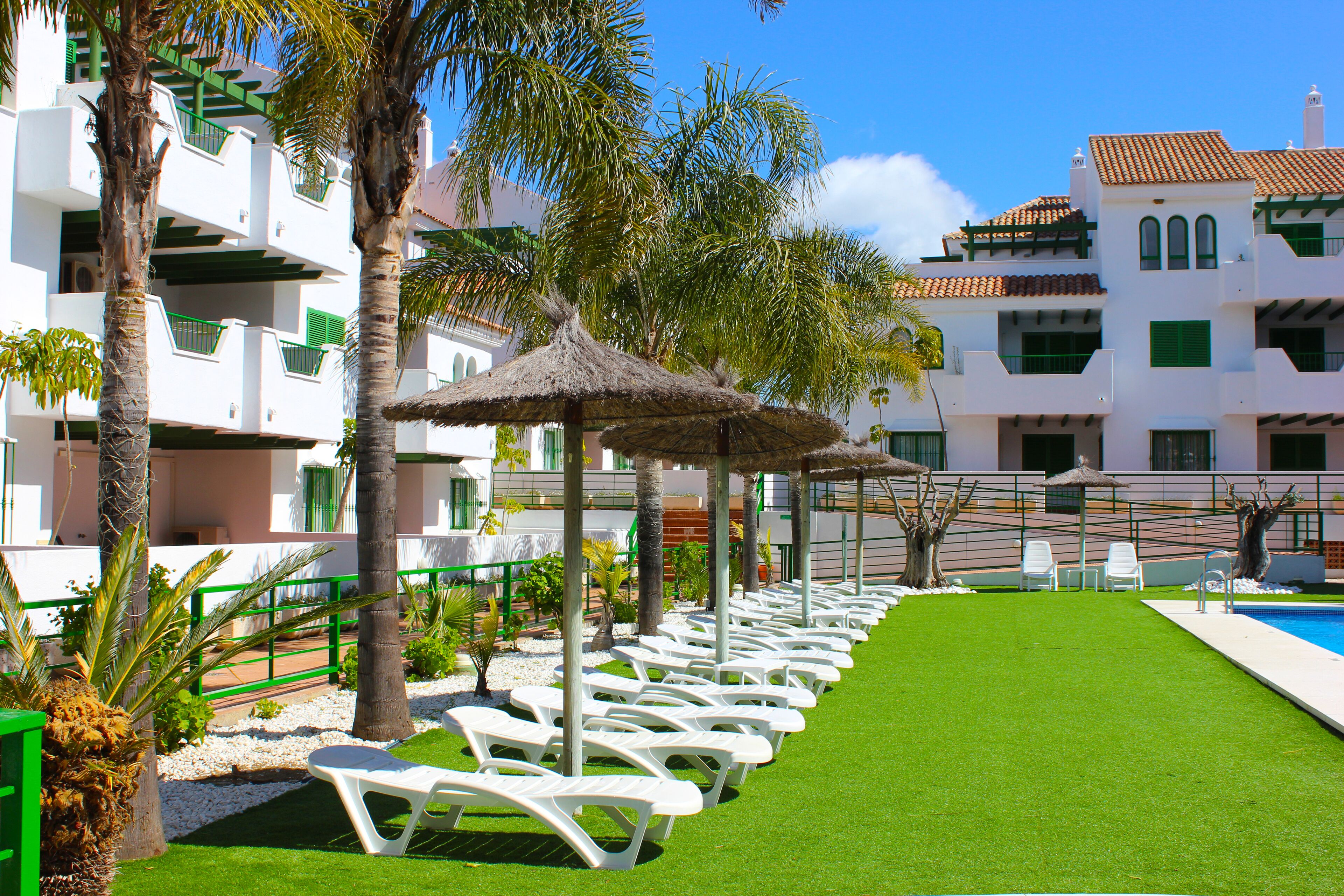 Een buitenzwembad, parasols bij het zwembad en ligstoelen