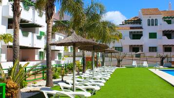 Een buitenzwembad, parasols bij het zwembad en ligstoelen