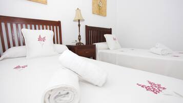 A hotel room with two beds, white linens, and floral pillows.