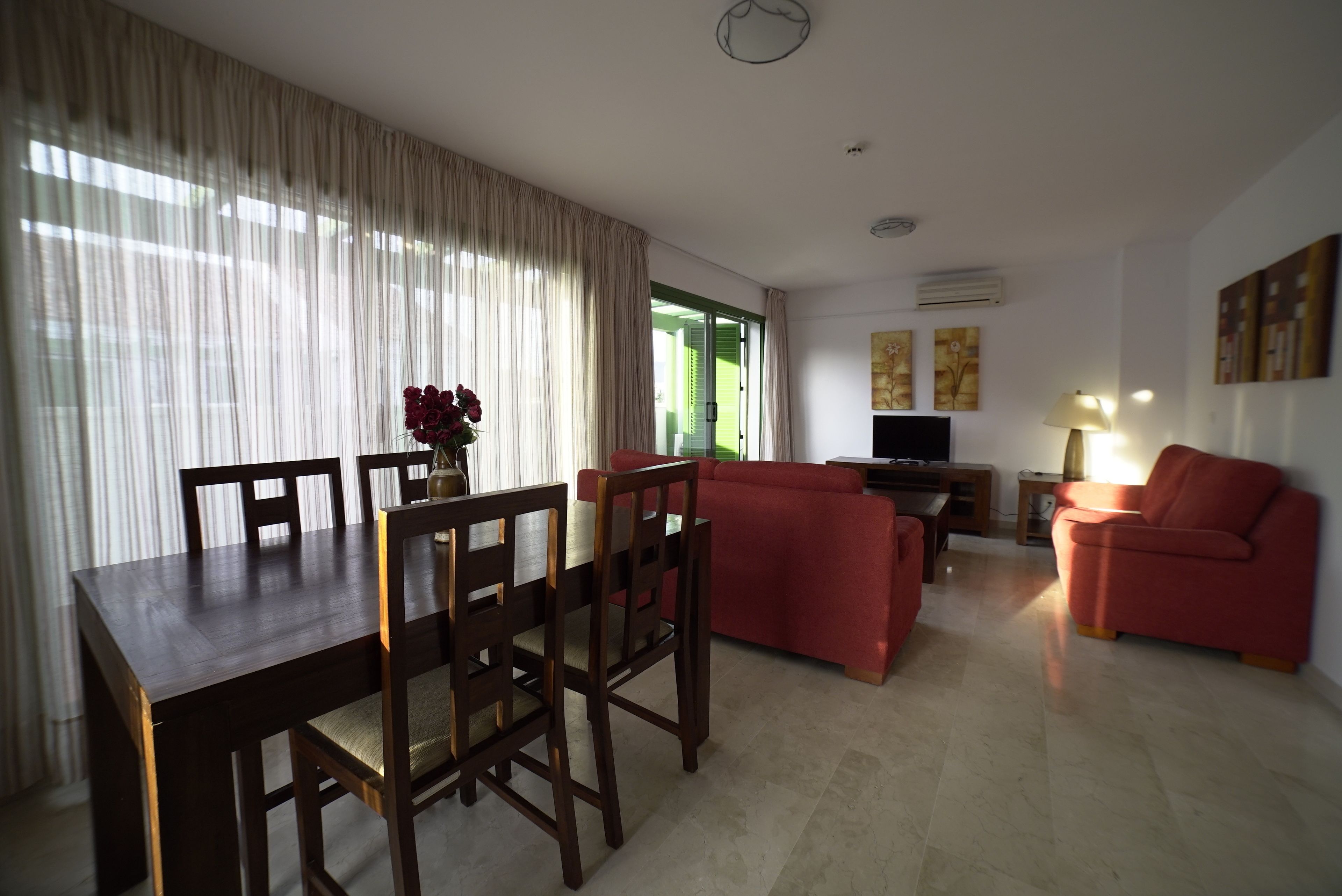 Una sala de estar con una mesa de comedor, sofás rojos y un televisor.