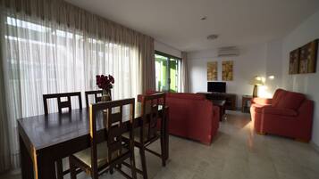 Una sala de estar con una mesa de comedor, sofás rojos y un televisor.