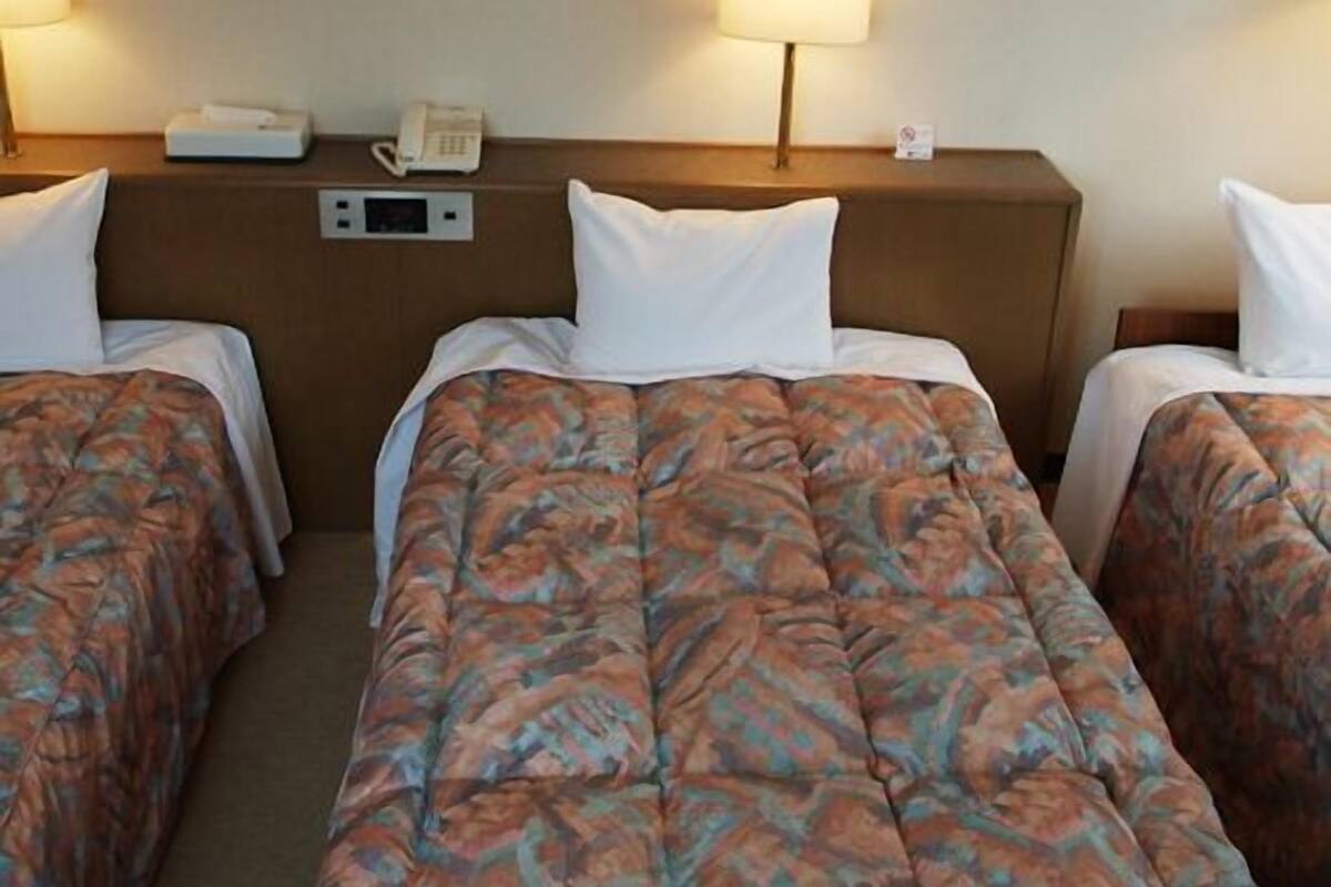 Habitación de hotel con dos camas, teléfono en la mesita de noche y una lámpara.