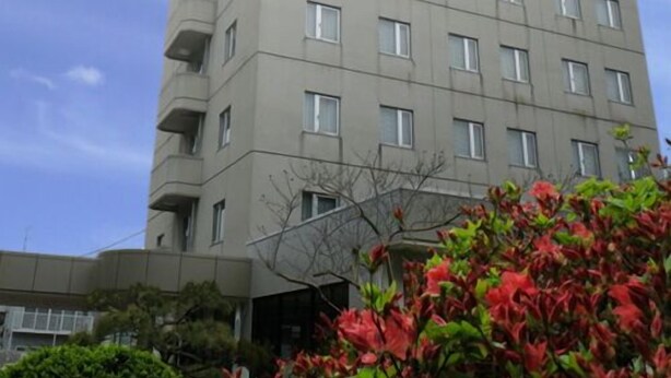 Um edifício com várias andares, fachada plana, diversas janelas e varandas.