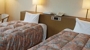 Duas camas de hotel com roupa de cama estampada, abajures, um telefone e um painel de controle na cabeceira.