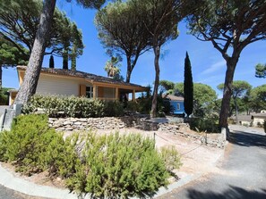 A house with a stone wall, a covered porch, and a clear blue sky.