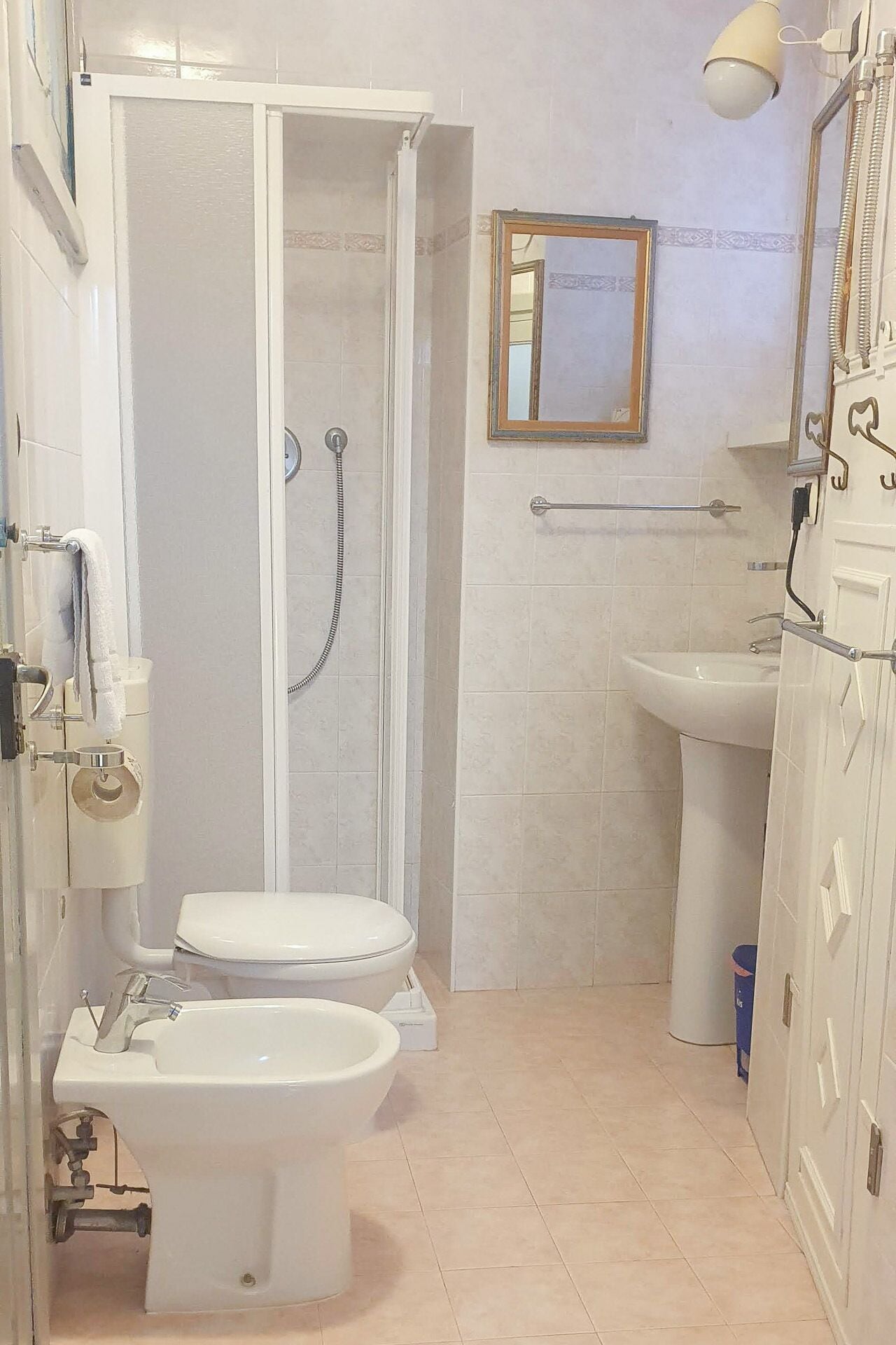 Un baño con ducha, inodoro, bidé, lavamanos y un espejo en la pared.