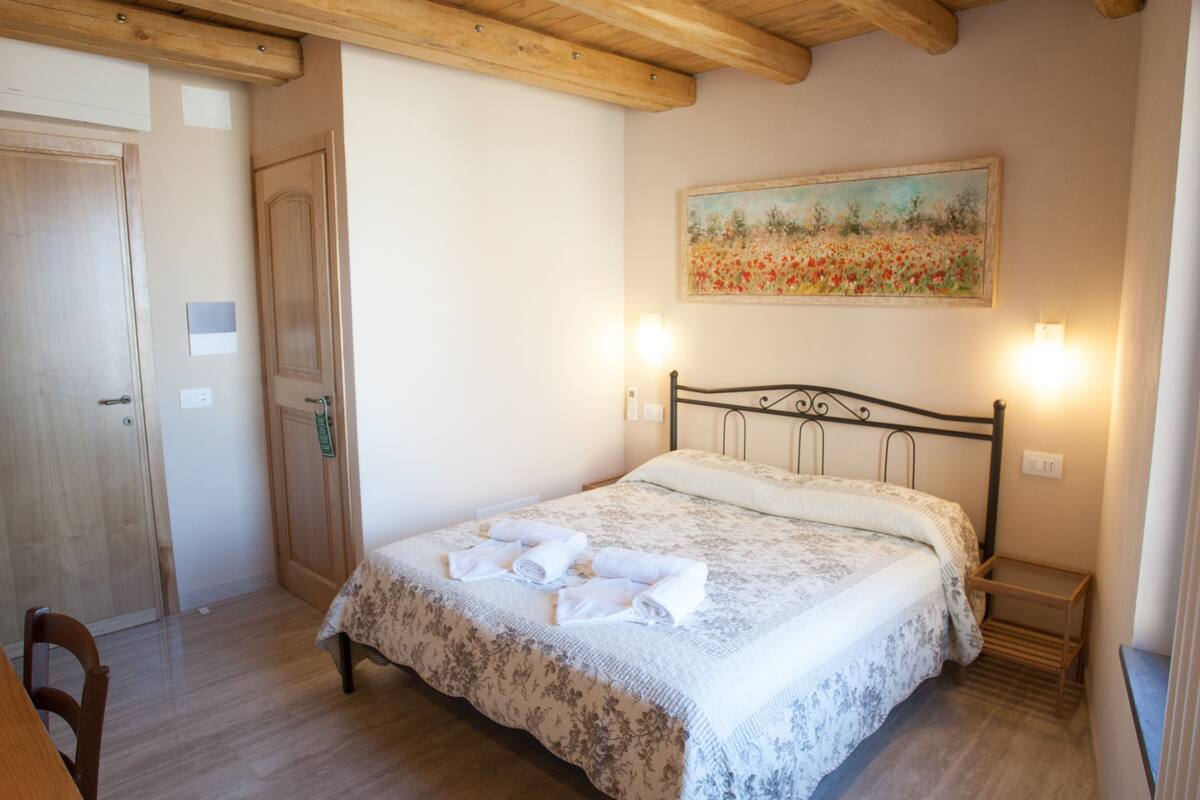 Ein Schlafzimmer mit einem Bett, einem Bild an der Wand und einer Holzbalkendecke.