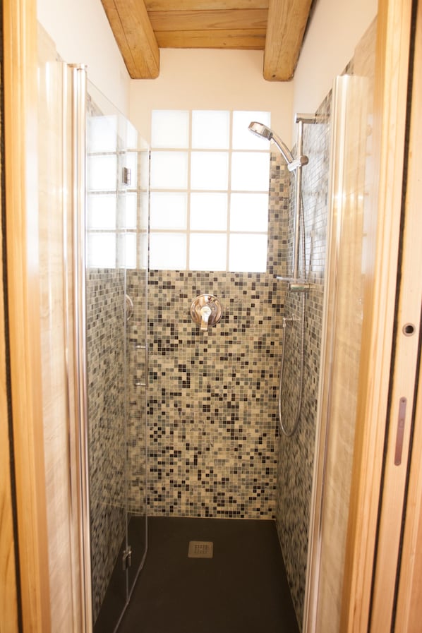 A shower with mosaic tile walls, a window, and wooden ceiling beams. - Scorci Di Mare (Riomaggiore)