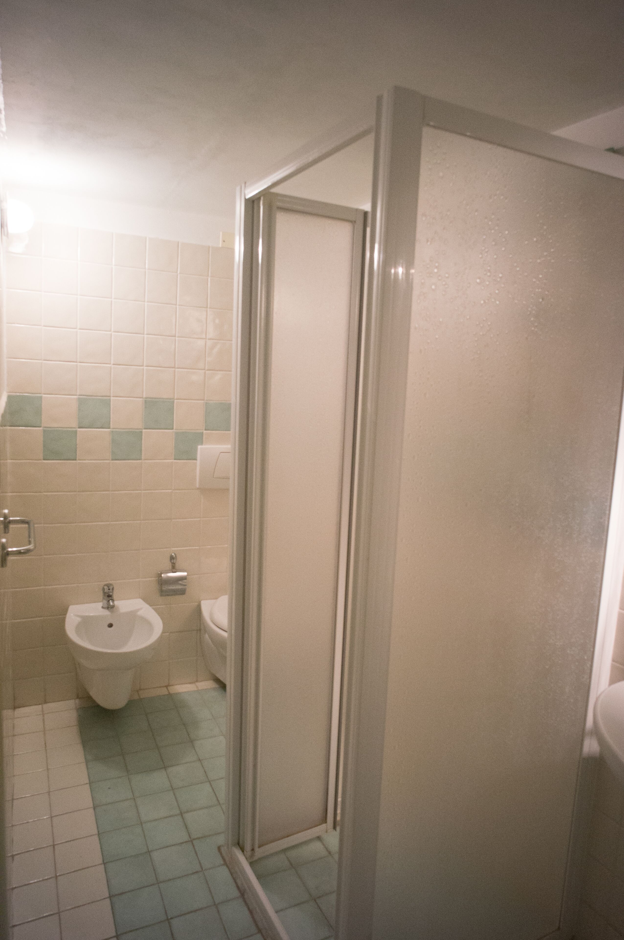 Un baño con inodoro, bidé y cabina de ducha de vidrio.