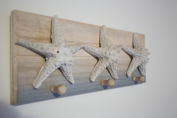 A wooden wall-mounted piece with three starfish and two small round objects.