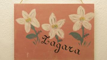 Ein Wandbehang mit drei weißen Blumen und dem Schriftzug "Laguna" auf beigem Hintergrund.
