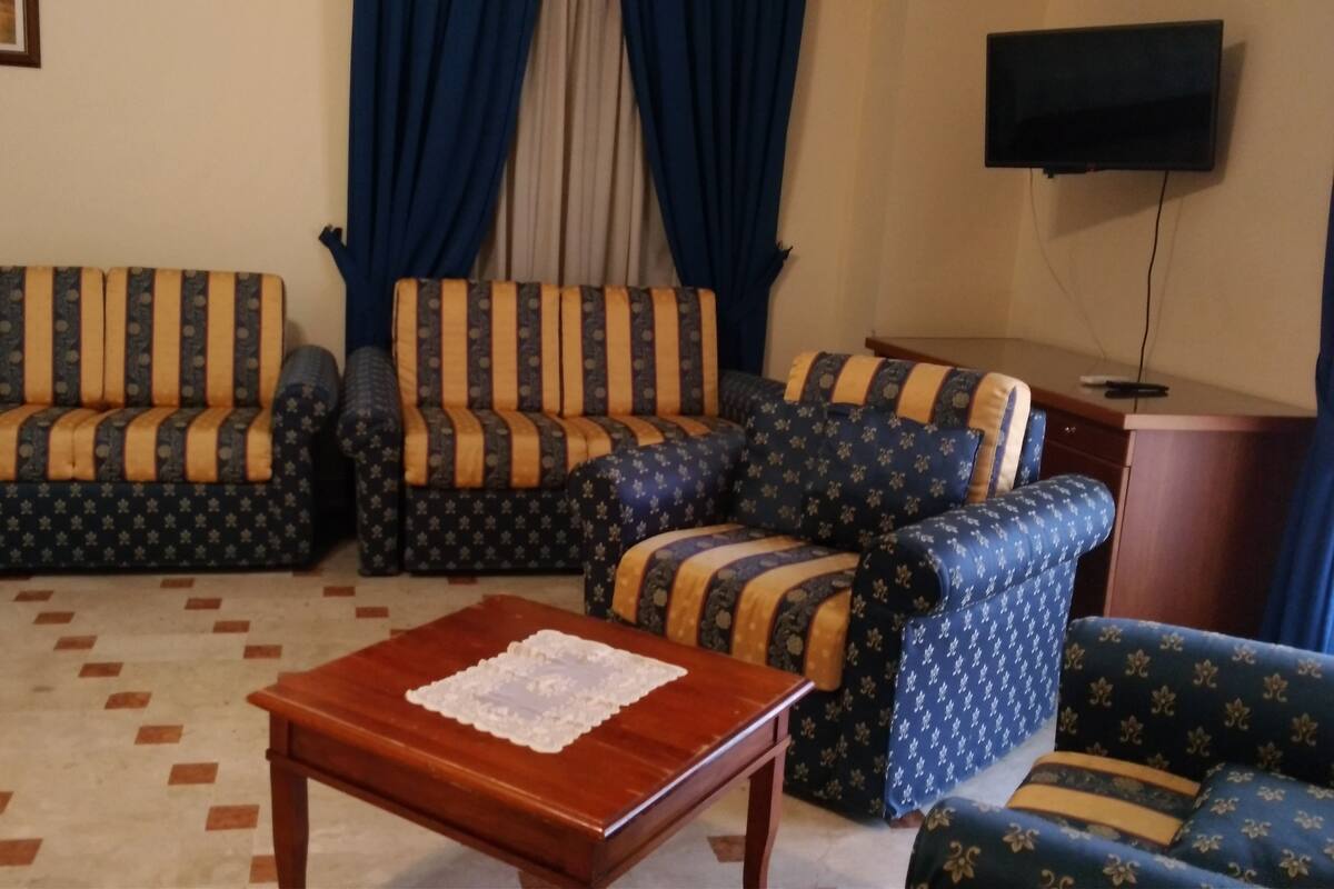 Ein Wohnzimmer mit einer Sofagarnitur, einem Couchtisch und einem Fernseher.