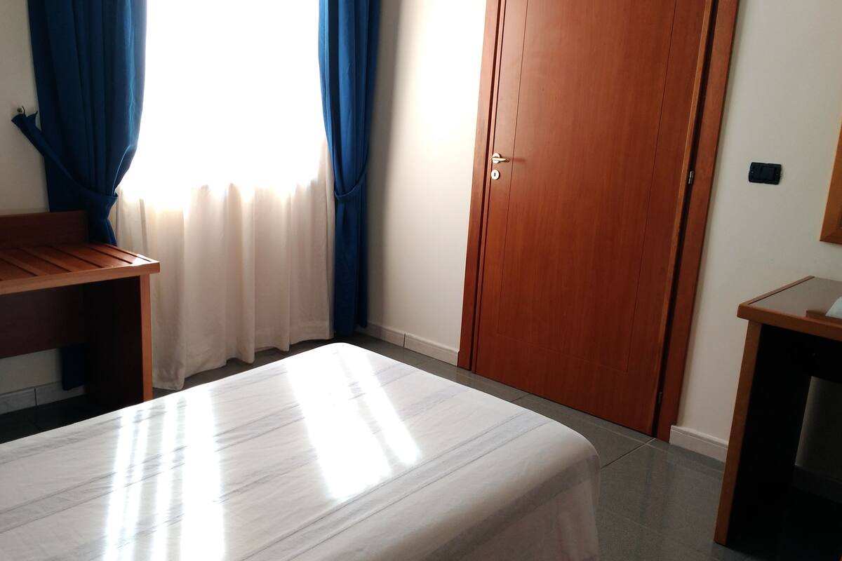 Ein Schlafzimmer mit einem Bett, einem Holztisch, einem Kleiderschrank und einem kleinen Tisch mit Spiegel.