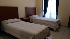 Two single beds with wooden headboards, a small bedside table, and a window with curtains. - Hotel la Falconara (Castrovillari)