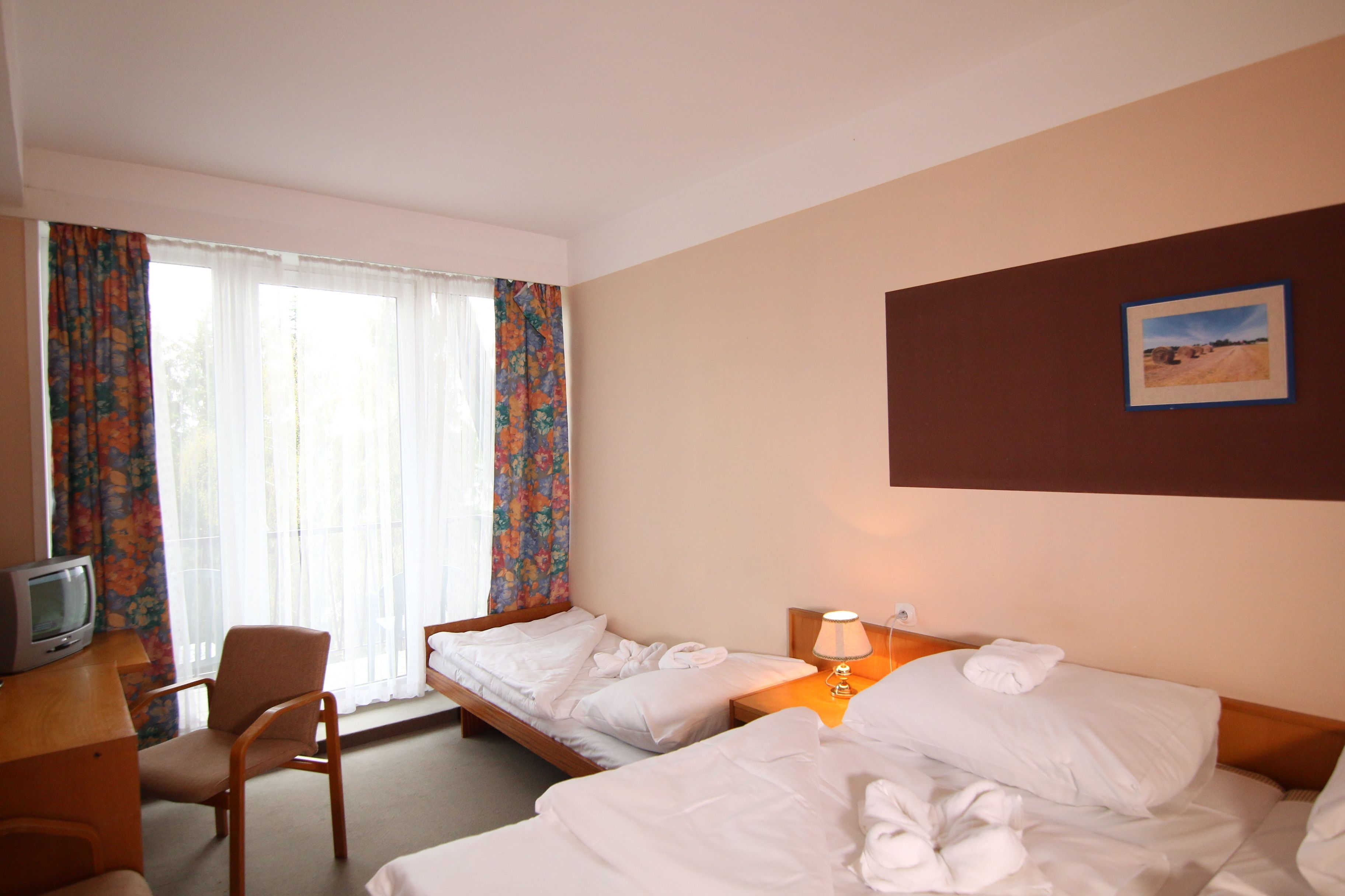 Een hotelkamer met twee bedden, een bureau met een televisie en een stoel.