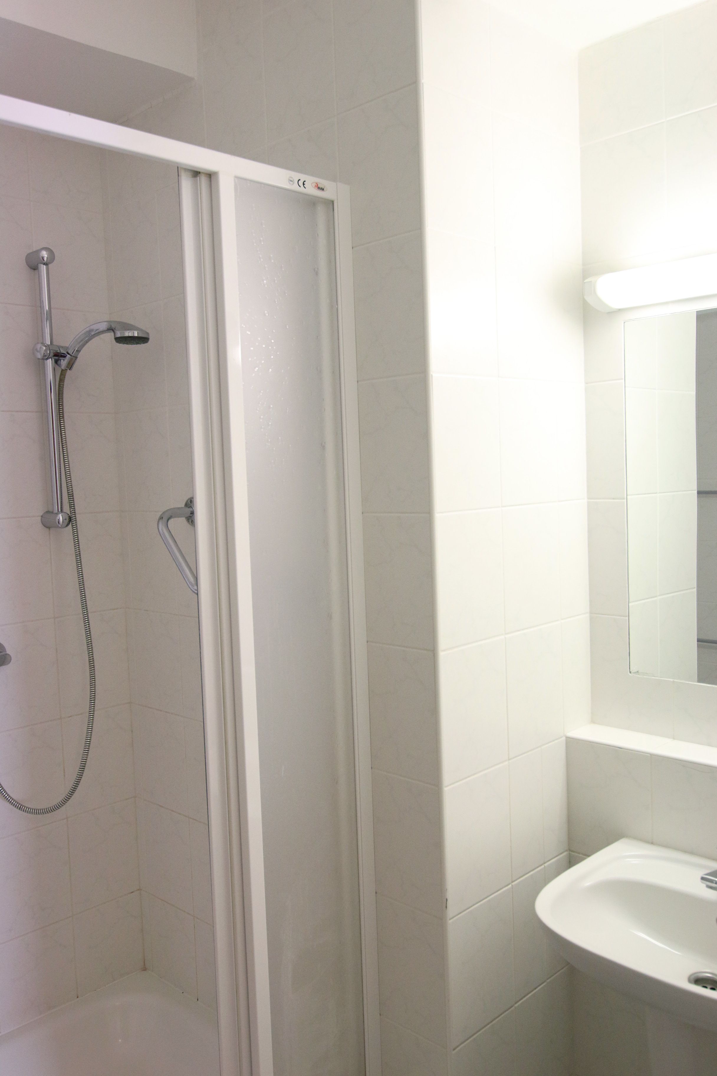 A bathroom with a shower, a sink, and a mirror.
