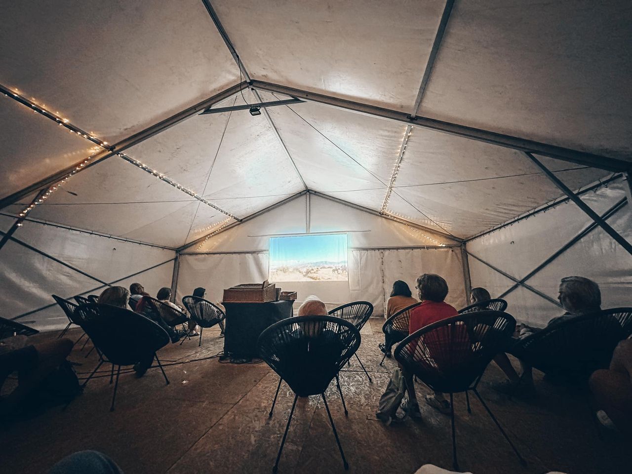 A tent with a central table and chairs arranged for a group setting.
